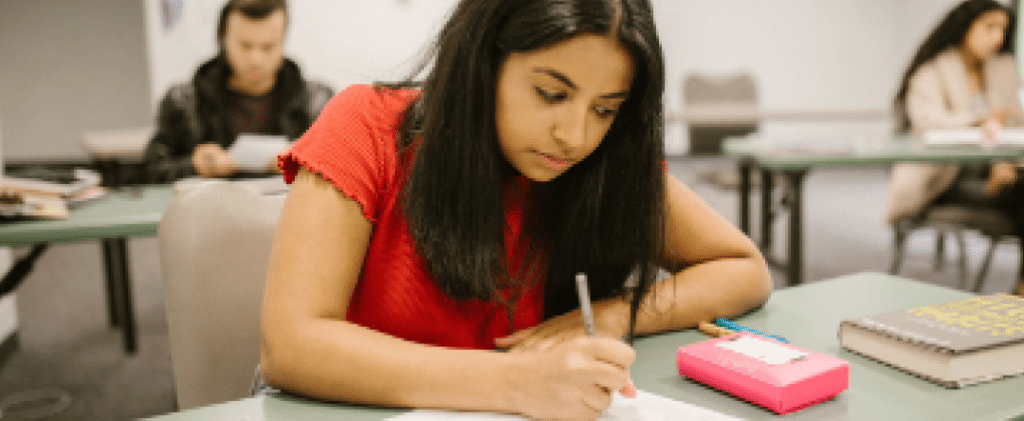 Young female student writing at assignment in class